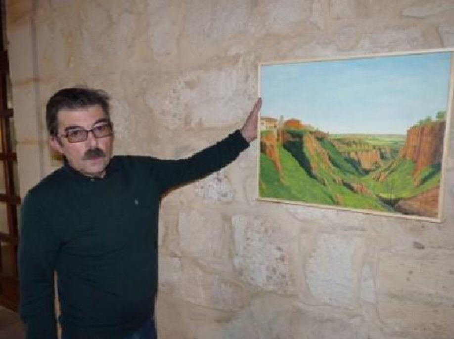 El artista junto a un cuadro.