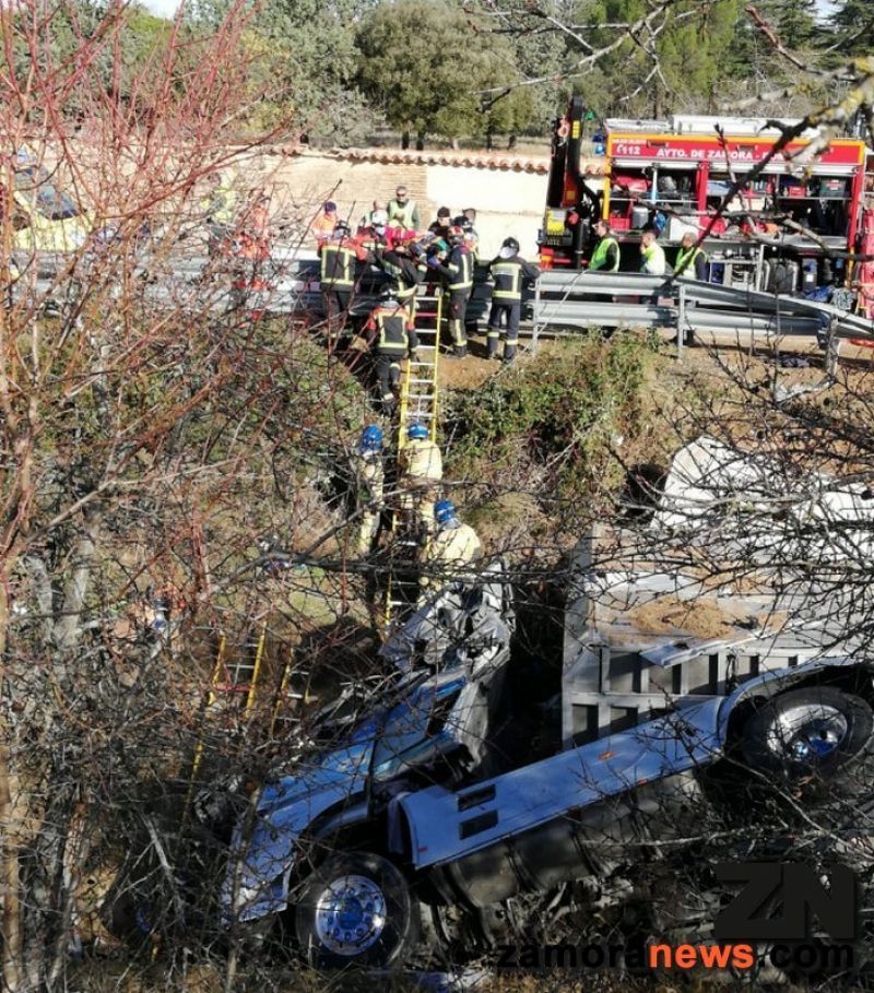 Los bomberos socorren y sacan de un camión a su conductor herido que ha sido evacuado en helicóptero tras el vuelco en una cuneta a la altura de Peleagonzalo